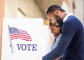 A young man and woman voting at a voting booth in a US election.