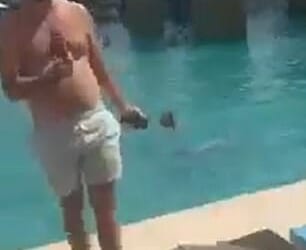 A man wearing swimming trunks at the side of the pool while strikes are intercepted above