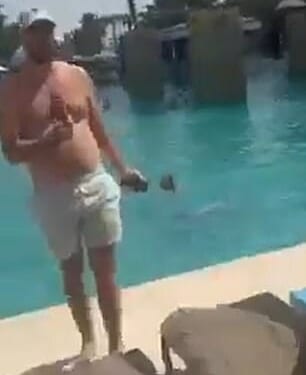 A man wearing swimming trunks at the side of the pool while strikes are intercepted above