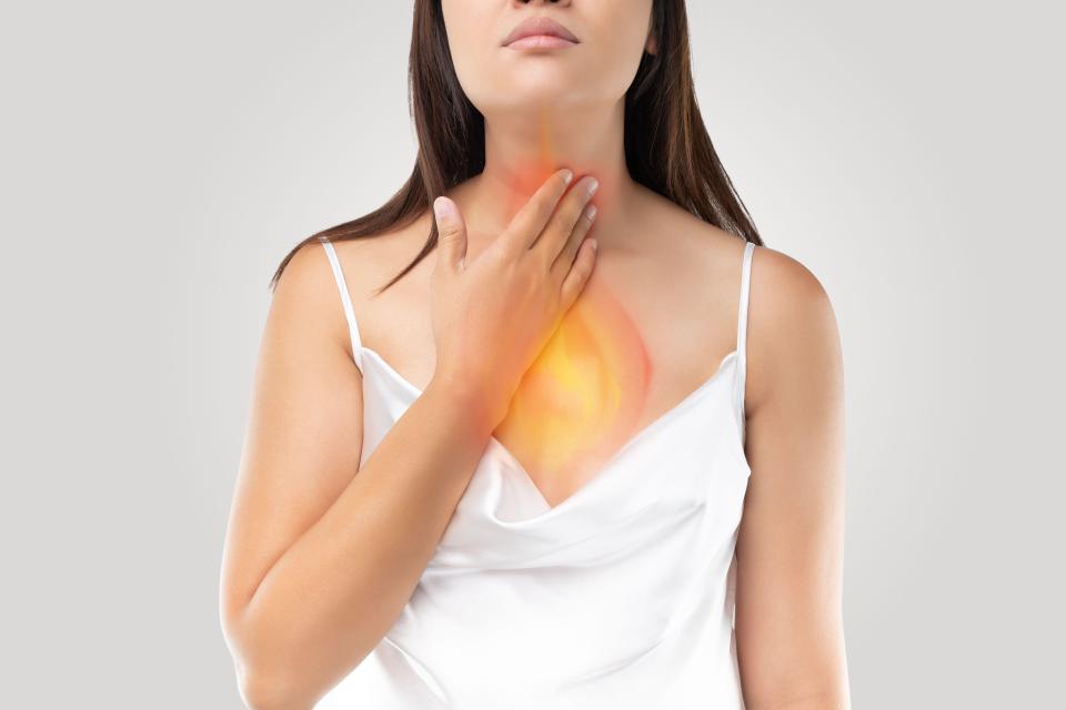 A woman suffering from acid reflux or Heartburn on gray Background