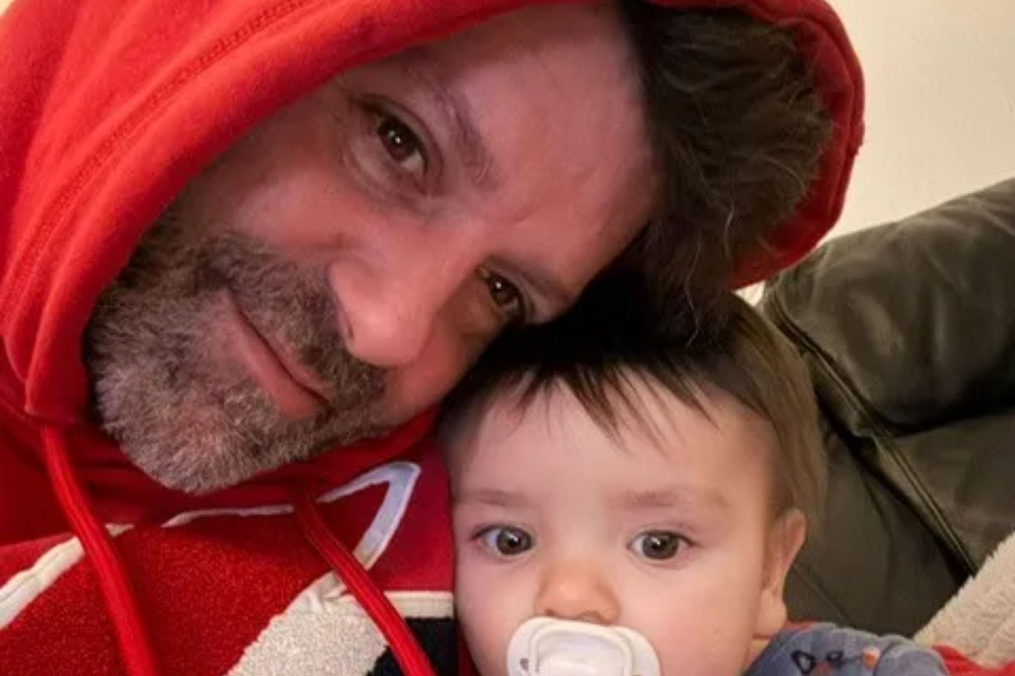 An image collage containing 1 images, Image 1 shows Man in red hoodie with a baby holding a pacifier