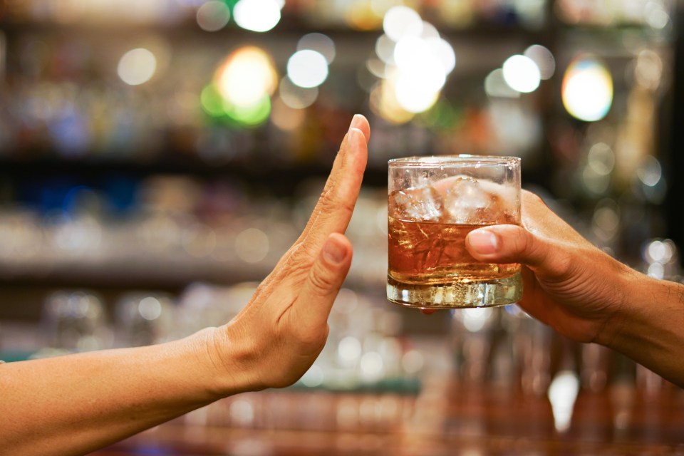 A person making a stop gesture to a glass of alcohol.