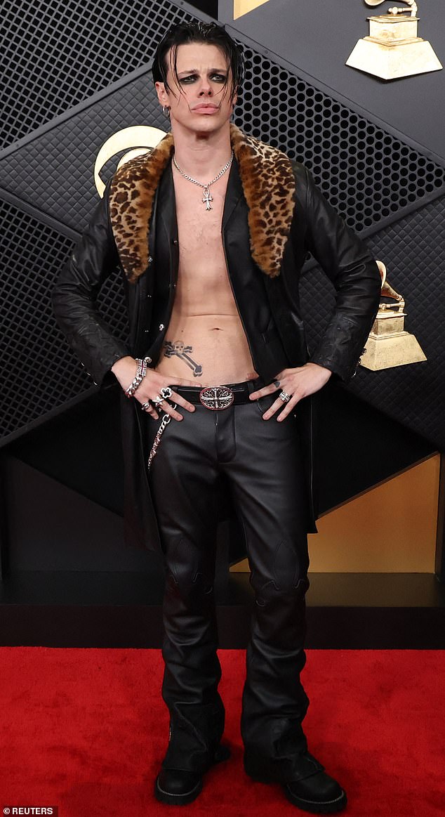 Missing something? British artist Yungblud went shirtless on the Grammys 2026 red carpet, as he donned only a black leather jacket on top, complete with a leopard-print fur collar. On the bottom, he wore tight leather pants along with chunky black boots. He completed his look with a silver, Chrome Hearts necklace and tons of silver rings and bracelets