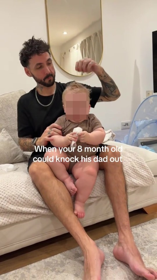 A man sitting on a couch with a baby on his lap, with text overlay, "When your 8 month old could knock his dad out."