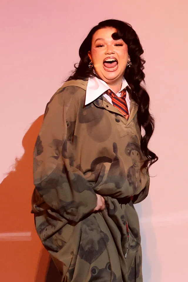 Molly Burke in a green camouflage sweatshirt and red striped tie at the 68th Grammy Awards.