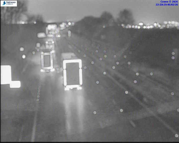 Monochrome image of nighttime highway traffic with blurred lights.