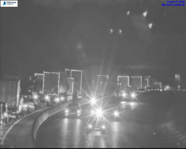 Nighttime traffic on a highway, with bright headlights from vehicles.