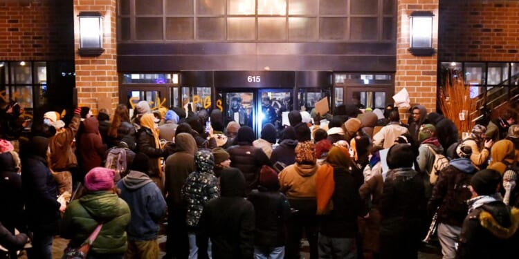 Anti-ICE demonstrators protest outside the graffiti-tagged Graduate Hotel, where federal immigration agents are believed to be staying in Minneapolis, Minnesota, on Jan. 13, 2026.
