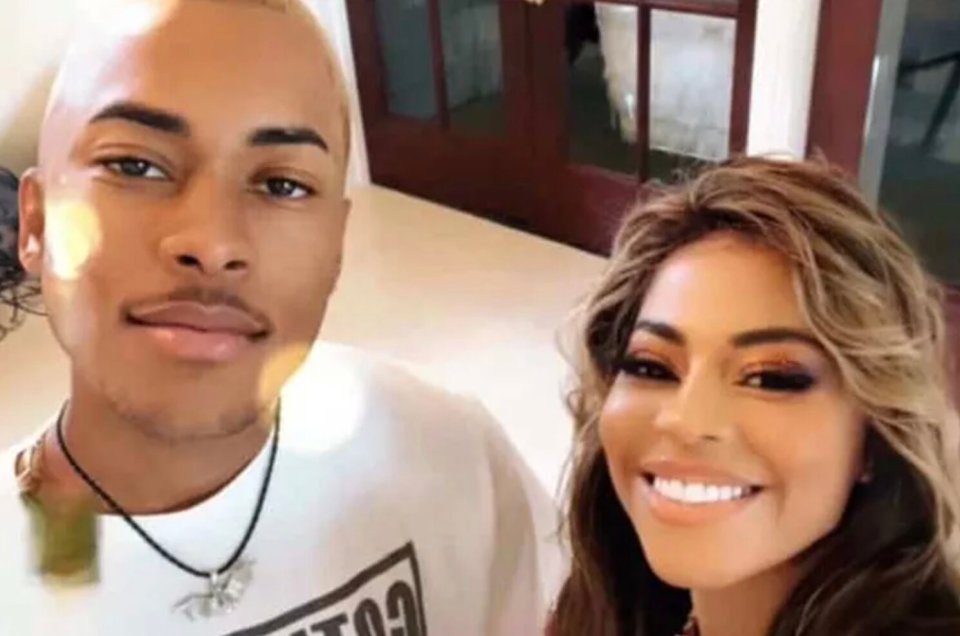 A young man with blonde hair and a woman with wavy brown hair smiling together.