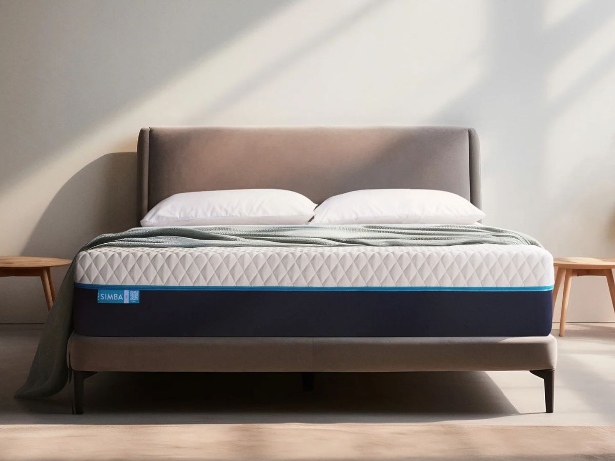 Simba mattress with a white and blue design on a bed frame with pillows and a blanket.