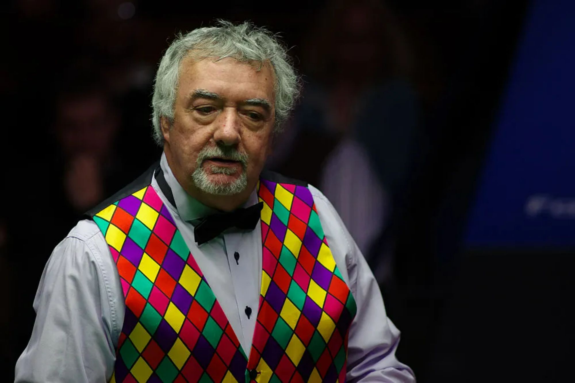 An image collage containing 1 images, Image 1 shows John Virgo during an exhibition match at the 2015 Betfred World Snooker Championship