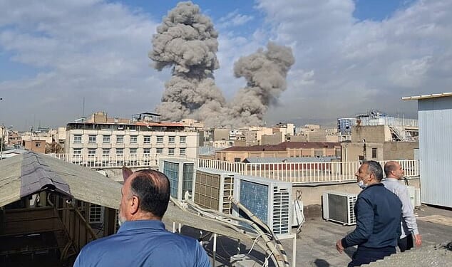 People watch as smoke rises on the skyline after an explosion in Tehran, Iran, on Saturday
