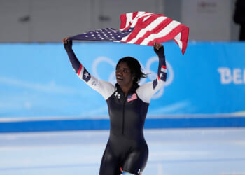 Erin Jackson of the United States hoists an American flag after winning the gold medal in the speedskating women's 500-meter race at the 2022 Winter Olympics in Beijing.