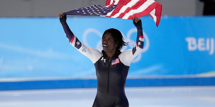 Erin Jackson of the United States hoists an American flag after winning the gold medal in the speedskating women's 500-meter race at the 2022 Winter Olympics in Beijing.