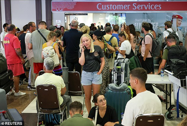 Stranded passengers wait near Emirates Airways customer service office after flights to Doha, Dubai, and Abu Dhabi were cancelled