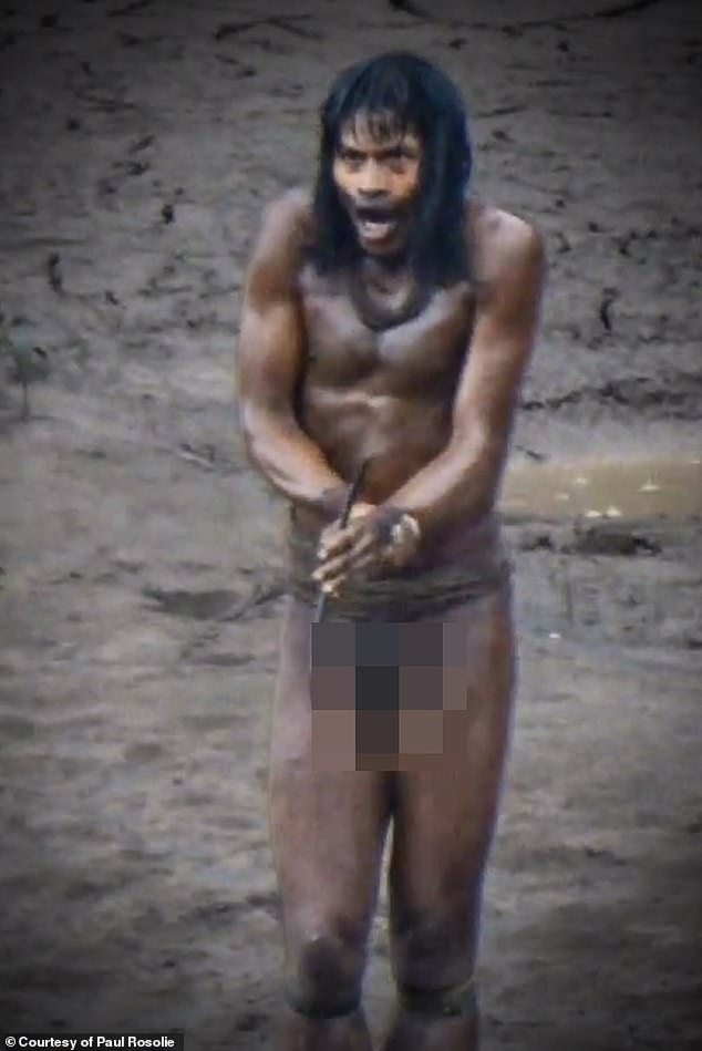 A Mashco Piro man shouting in the rain, trying to communicate with the villagers across the river