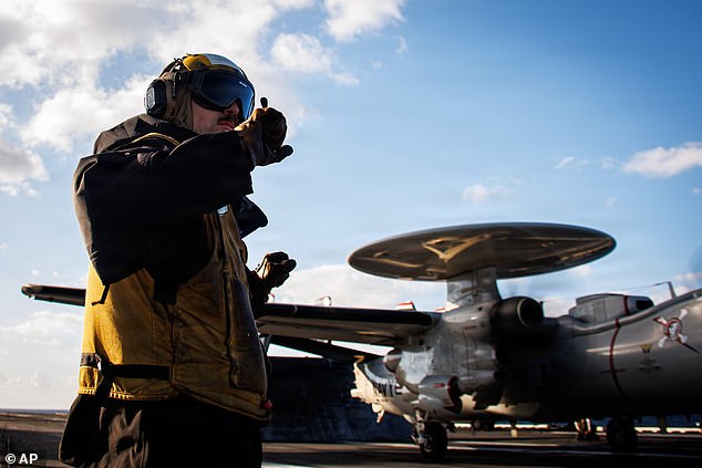 This image provided by U.S. Central Command shows a U.S. Navy sailor preparing a E-2D Hawkeye aircraft for launch on the flight deck of the USS Gerald R. Ford (CVN 78), in support of Operation Epic Fury on Saturday