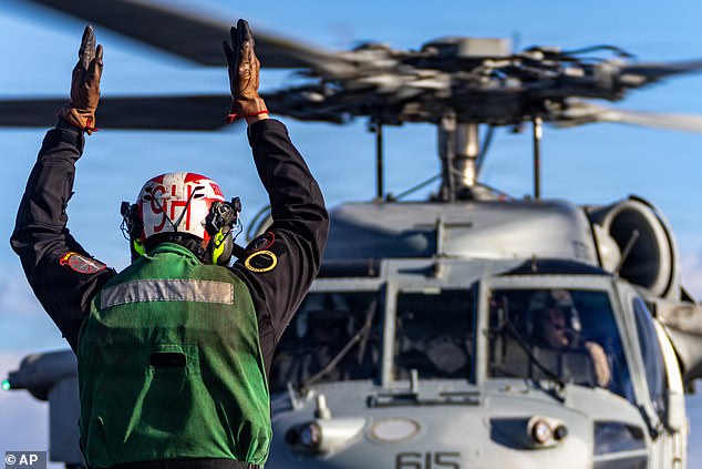 This image provided by U.S. Central Command shows a U.S. Navy sailor signaling to a MH-60S Sea Hawk helicopter before launch on the flight deck of the USS Gerald R. Ford (CVN 78), in support of Operation Epic Fury on Saturday
