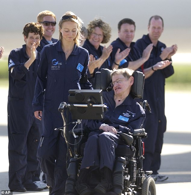 Astrophysicist Hawking is assisted off the tarmac at the Kennedy Space Center by his carer, Monica Guy, as he is applauded by members of the flight crew after completing a zero-gravity flight in Cape Canaveral, Florida