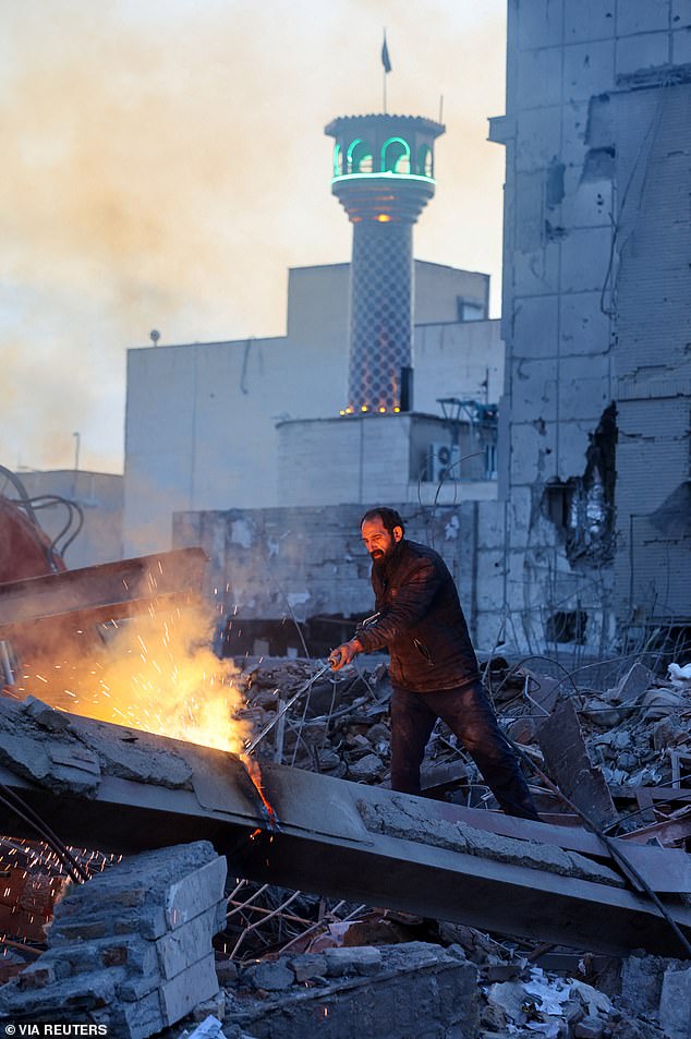 An Iranian man works amid the debris following the US and Israeli attacks on Tehran over the weekend