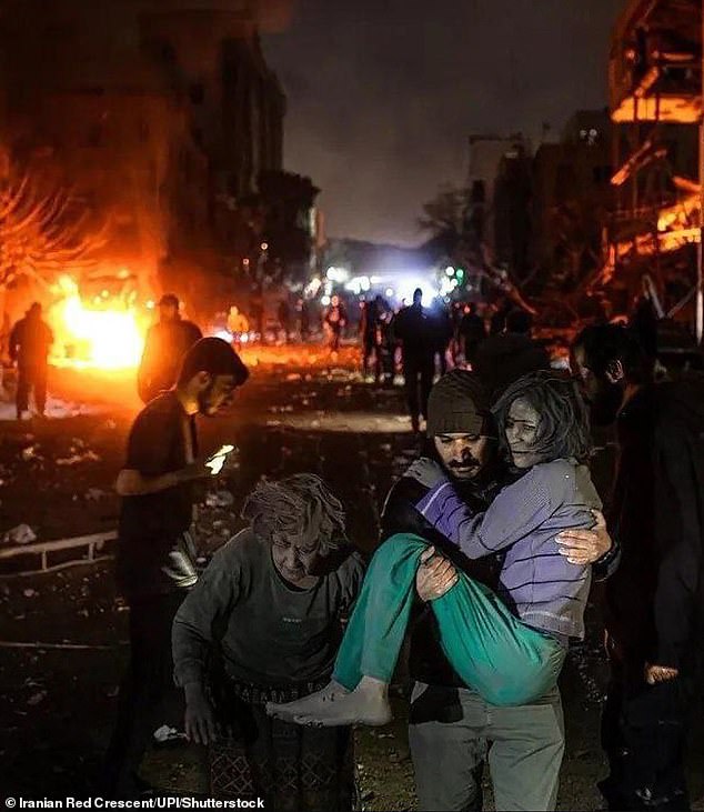 A man carries an injured woman at the site of US-Israeli airstrikes in Tehran, Iran, on Monday
