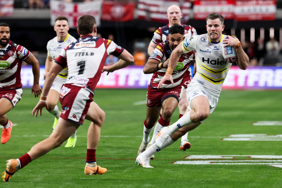 Rugby player running with the ball during a Wigan Warriors vs Warrington Wolves game.
