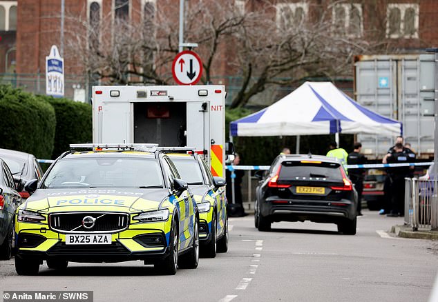 Police vehicles and an ambulance next to the scene of the stabbing, which is covered by a tent
