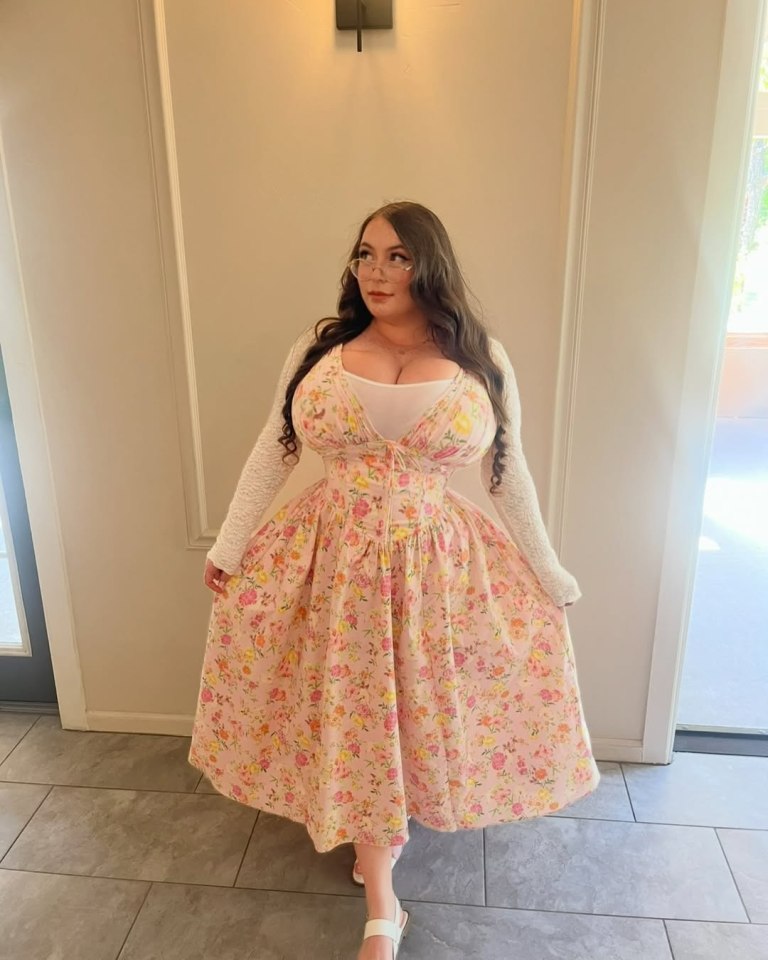 Woman in a pink floral dress and white cardigan.