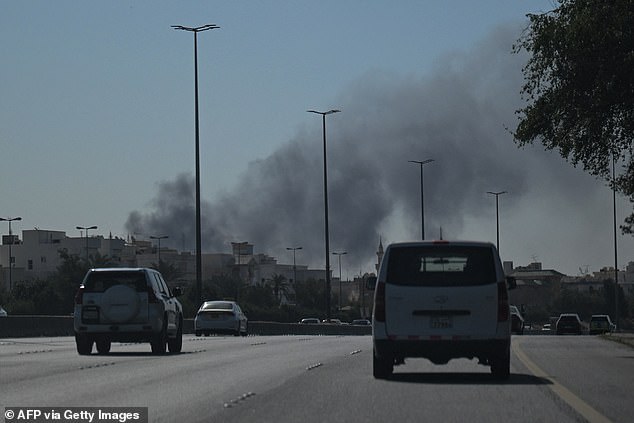 Motorists are seen driving along a street as smoke rose from a reported Iranian strike in an area near where the US Embassy is located in Kuwait City