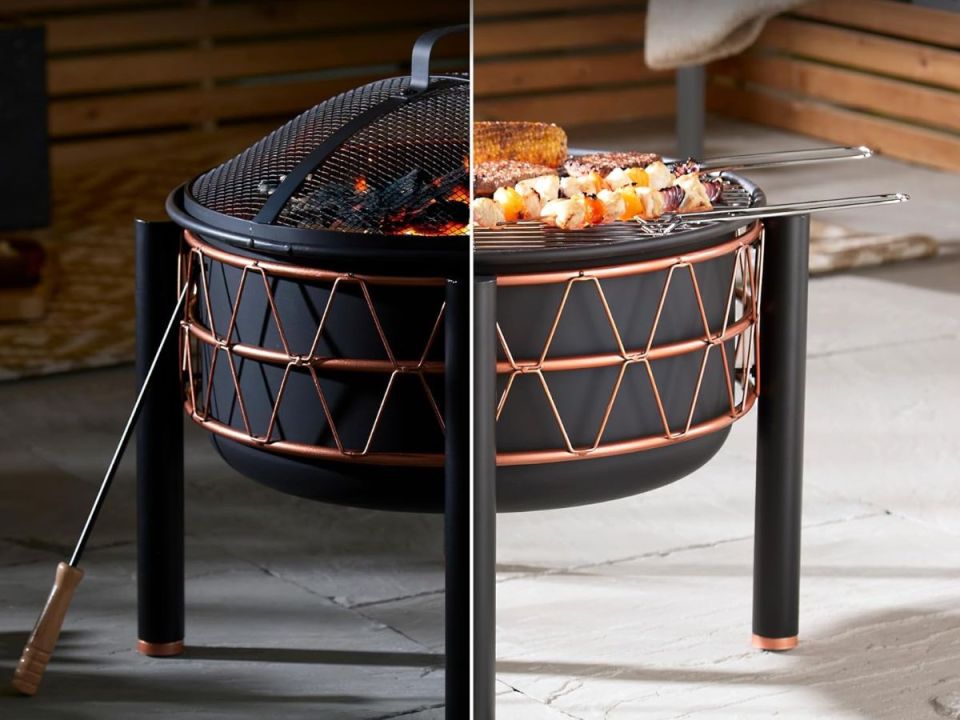 A black and copper fire pit, with one side showing a fire and the other side showing a grill with food.