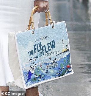 She carried a white handbag with the cover of her book on the front