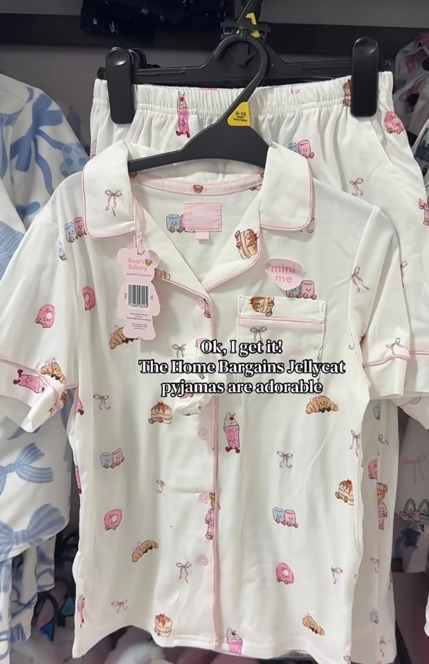 White pajamas with pink trim, covered in illustrations of sweet food items, hanging on a rack.