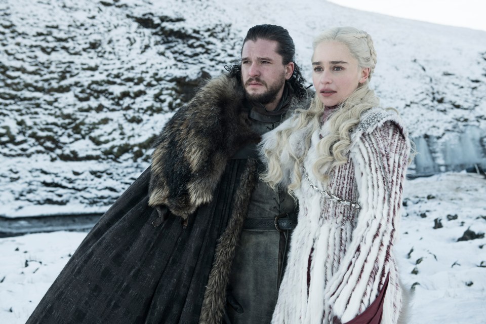 Jon Snow and Daenerys Targaryen stand in the snow, wearing fur and winter clothing.