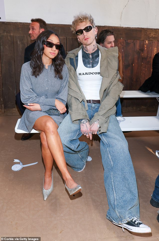 He was spotted in flared jeans, a white tank top with the word 'hardcore' in black print, and a pale green structural jacket