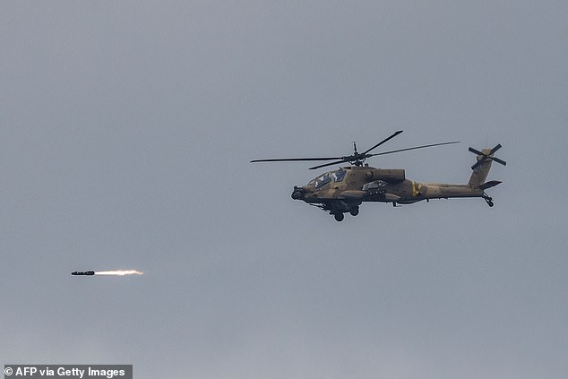 An Israeli Air Force AH-64 Apache attack helicopter fires rockets while flying at a position along the border between northern Israel and southern Lebanon on March 4