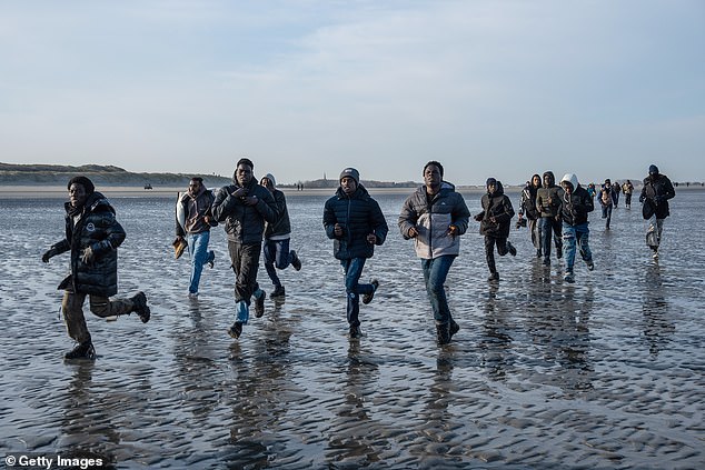 Migrants sprint across Gravelines beach in northern France earlier this week to board smugglers' dinghies bound for Britain