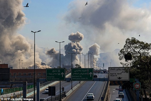 Motorists drive along an expressway as plumes of smoke rise after a strike in Tehran on March 5, 2026