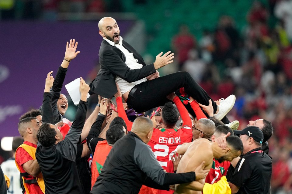 Morocco coach Walid Regragui is lifted and cheered by his players.