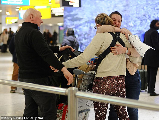 Mrs Cooper hugs her family in Heathrow's arrivals hall after flying in on Thursday evening with her husband and three children