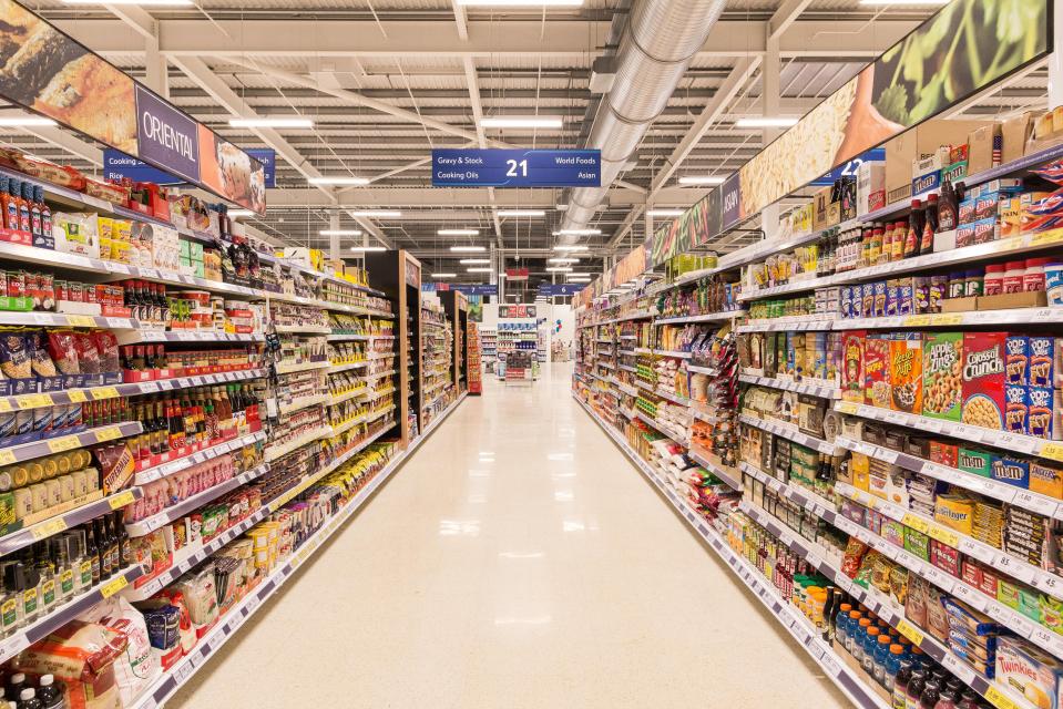A long aisle in a Tesco Extra supermarket, with shelves full of various food products on both sides.