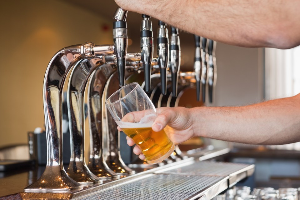 Bartender pouring a pint of beer from a tap.
