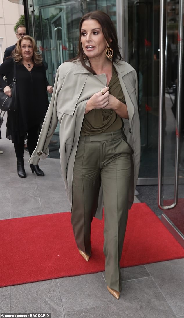 She paired the look with an oversized khaki trench coat slouched over her shoulders and patent mustard stilettos