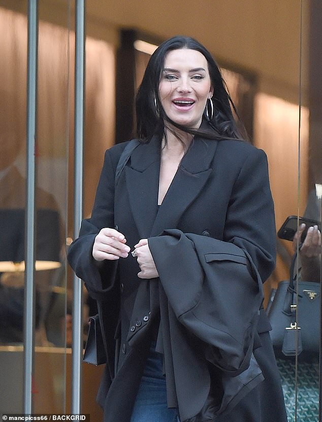 The beauty traded her blazer for a stylish black long coat as she stepped out into the cold, rainy weather