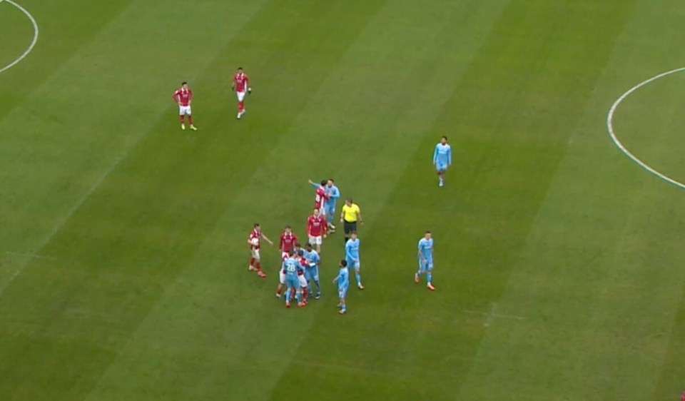 Soccer players and a referee on a green field.