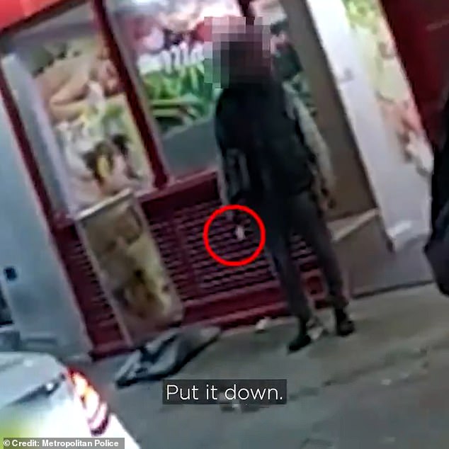 Her colleague echoes, 'Put it down!', as the pair approach the man (pictured), who is openly displaying the knife as he stands, seemingly completely relaxed, in front of a shop