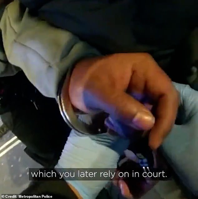 One of the officers pushes the man towards the wall and turns him around before quickly putting handcuffs on him, as he stands pressed against the shopfront