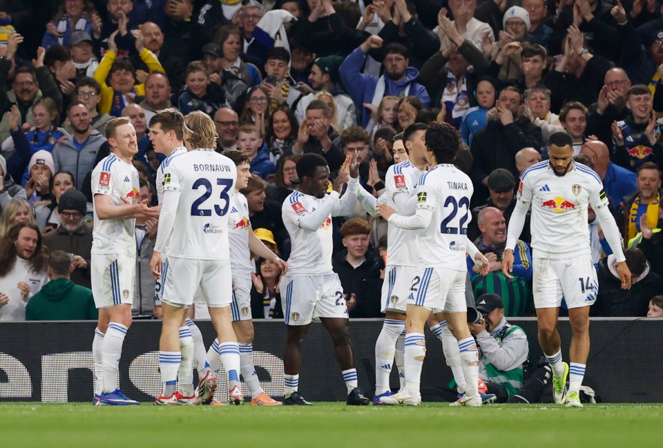 Sean Longstaff, wearing a white jersey with the number 23, celebrates scoring a goal with his teammates.