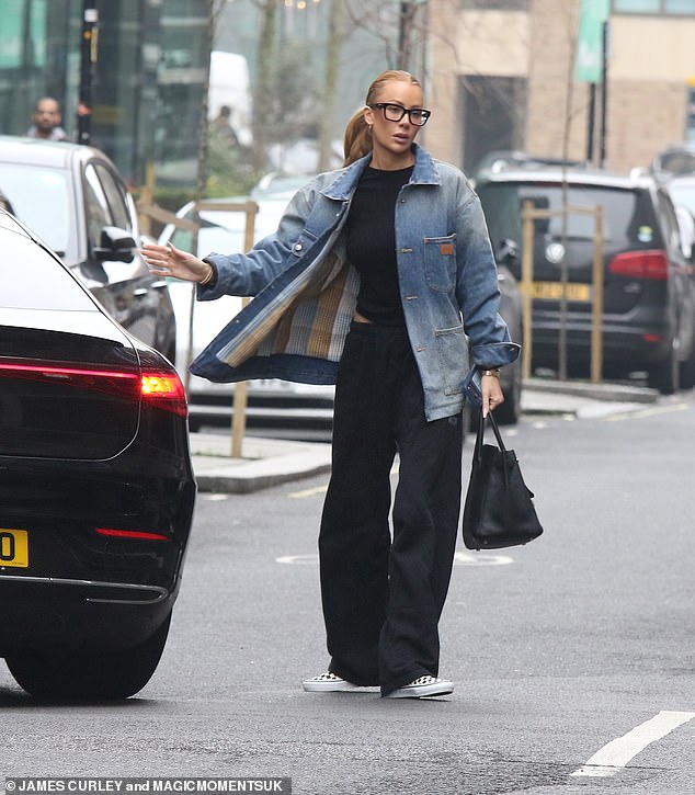 Olivia layered an oversized denim jacket over a black top, baggy trousers and toted her essentials in a £26,000 Birkin bag