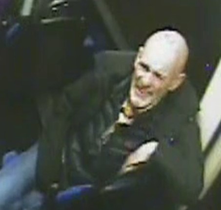CCTV image of a man with a bald head, dark jacket, and light shirt.