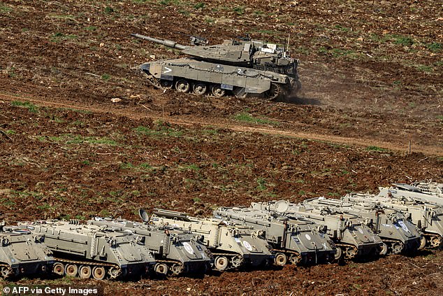 An Israeli Merkava main battle tank moves past armoured personnel carriers (APCs) deployed at a position in the upper Galilee in northern Israel near the Lebanon border on March 9